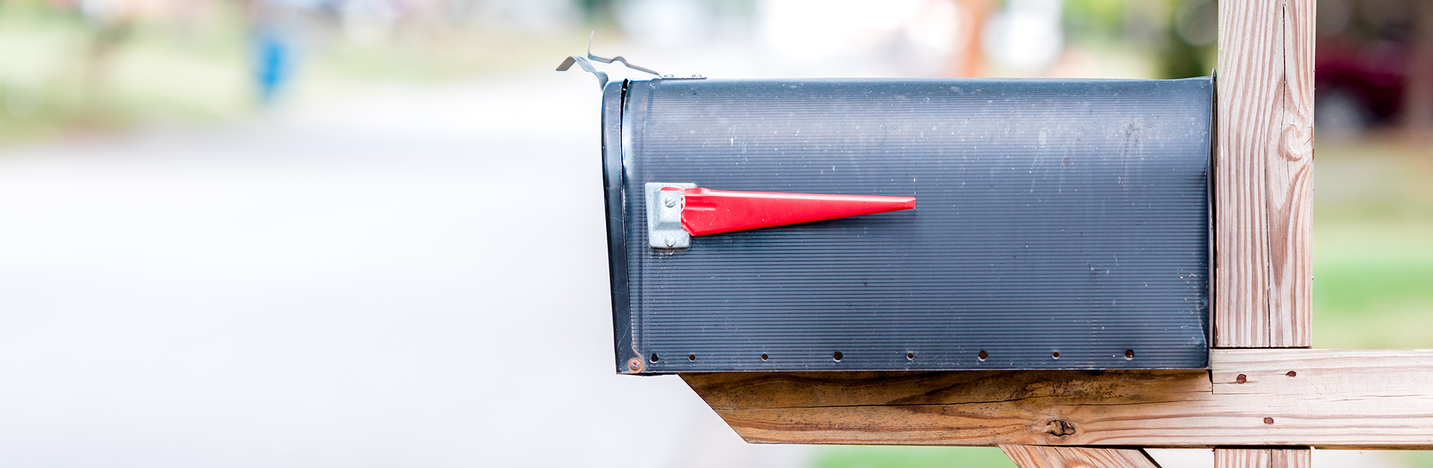 A side view of a back mailbox with its red flag down, mounted on two-by-fours.