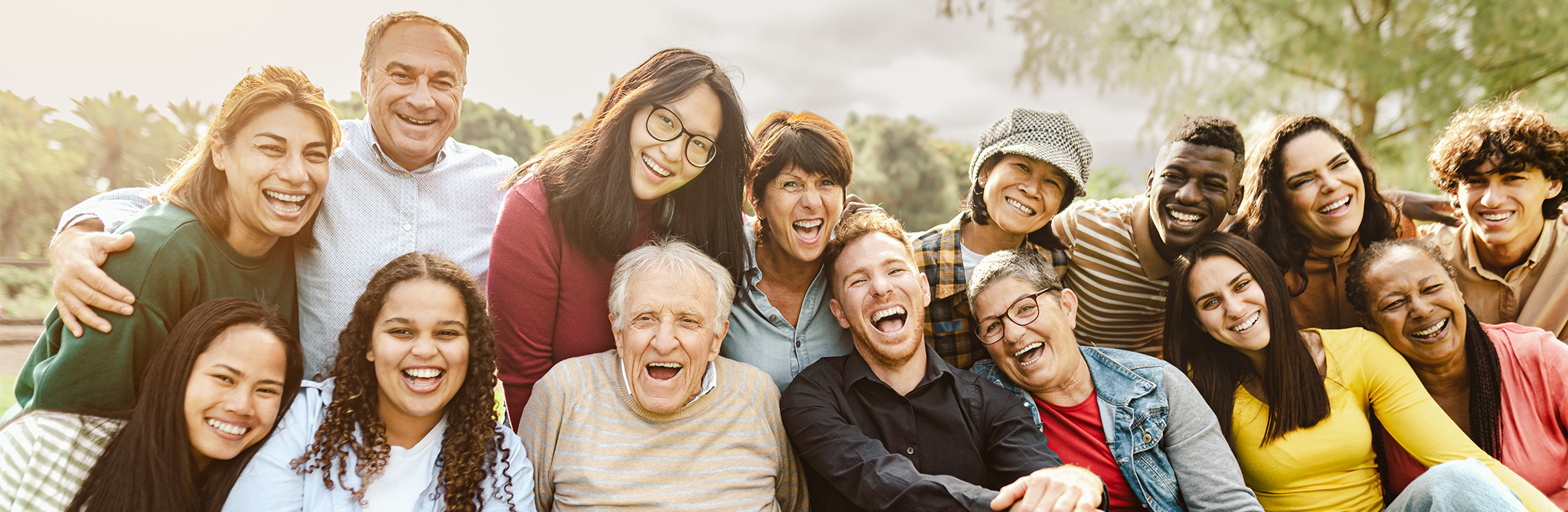 A mixed group of people smiling and laughing while their photo is being taken.