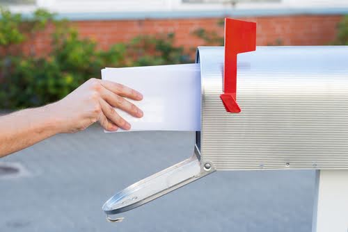 Hand putting mail in mailbox.
