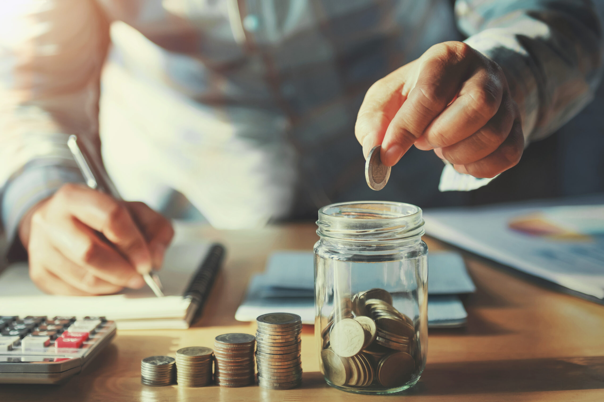 Person putting coins into a jar.
