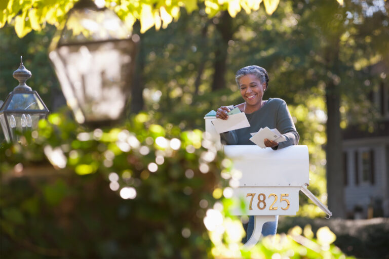 Woman looking at her mail by her mailbox.
