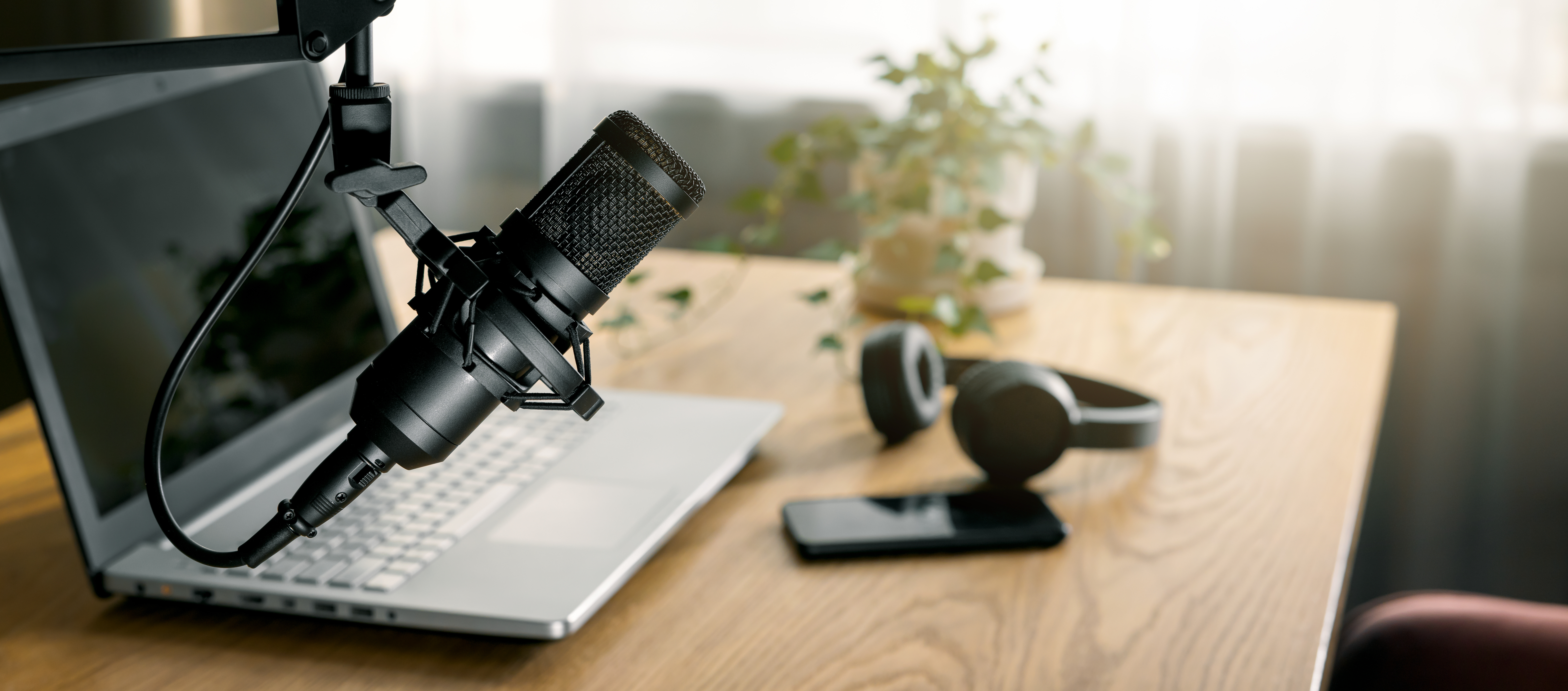 workplace of content creator with microphone, laptop and headphones. home studio for podcasting, online streaming, radio broadcasting. banner with copy space